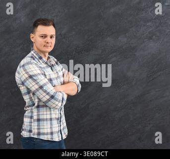 Junger Mann mit gekreuzten Armen über grauem Hintergrund Stockfoto