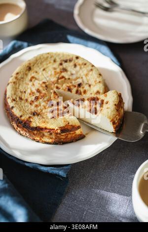 Nahaufnahme eines Stückes Basque Burnt Cheesecake auf einem Tisch, der mit einem Tortenheber serviert wird Stockfoto