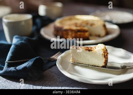Nahaufnahme eines Stücks Basque Burnt Cheesecake auf einem Tisch mit Tassen Kaffee für den Nachmittagstee Stockfoto