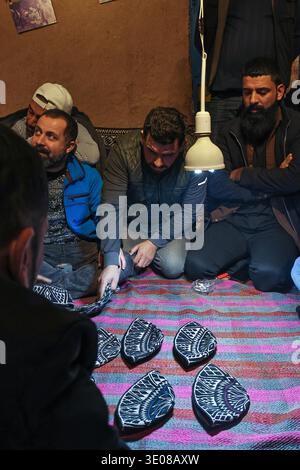 Erbil, Region Kurdistan, Irak. März 2026. Irakische kurdische Männer spielen das traditionelle Folklore-Spiel Klaw Klawne (Caps Game) während einer Ramadan-Nacht im Mali Hassan Hayran, einem historischen Schlammhaus im Shanidar Park in Erbil im Irak. Nach Iftar versammeln sich die Einheimischen, um das beliebte Ratesspiel zu spielen, ein geschätzter Ramadan-Brauch, der das kulturelle Erbe der Region Kurdistan bewahren soll (Foto: © Sabur Rashid/ZUMA Press Wire), NUR REDAKTIONELLE VERWENDUNG! Nicht für kommerzielle ZWECKE! Stockfoto