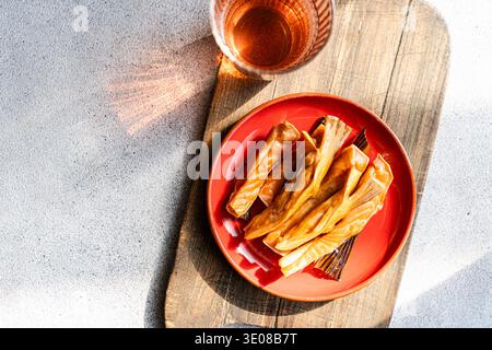 Blick von oben auf geräucherte Lachsfilets mit einem Glas Apfelessig auf einem hölzernen Schneidebrett Stockfoto