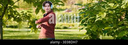 Ein junger Mann mit lockigen Haaren steht draußen in einer Sportjacke an einem Frühlingstag, Banner Stockfoto
