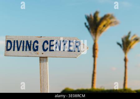 Holzschild mit Inschrift Tauchzentrum, Richtung tropischer Strand mit Palmen Stockfoto