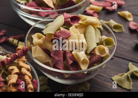 Verschiedene bunte Pasta in Glasschalen auf hölzernem Hintergrund Stockfoto