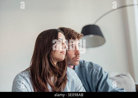 Ein junges Paar sitzt ruhig auf dem Sofa und sorgt sich um seine Zukunft und sein Geld. Trotz des Stresses finden sie in jedem anderen Trost und emotionale Unterstützung Stockfoto