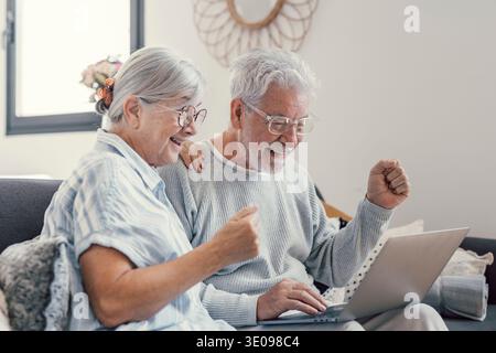 Senior reifes Paar durch gute unglaubliche Nachricht überrascht aufgeregt, unerwarteten Gewinnen, riesigen Shopping Verkauf Angebot auf der Website, erstaunt ältere im mittleren Alter fa Stockfoto