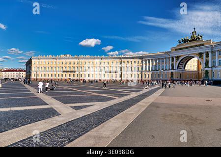 Die Leute laufen um das Generalstabsgebäude in der Nähe der Eremitage in Sankt Petersburg herum. Der helle Himmel ist klar an einem geschäftigen Tag. Stockfoto