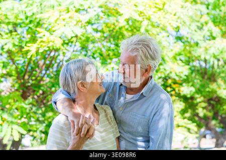 Wunderschönes, süßes Paar Senioren umarmt, Spaß zu haben und gemeinsam im Grünen Park zu genießen, lächelnd und entspannend. Zwei Rentner, die die Aufnahme begrüßen Stockfoto