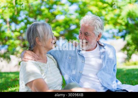 Wunderschönes, süßes Paar Senioren, die sich umarmen und einen zarten Moment draußen im grünen Park genießen und vor Glück lächeln. Zwei Rentner Stockfoto