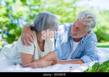 Wunderschönes, süßes Paar Senioren, die sich umarmen und einen zarten Moment draußen im grünen Park genießen und vor Glück lächeln. Zwei Rentner Stockfoto