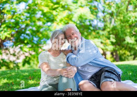 Wunderschönes, süßes Paar Senioren, die sich umarmen und einen zarten Moment draußen im grünen Park genießen und vor Glück lächeln. Zwei Rentner Stockfoto