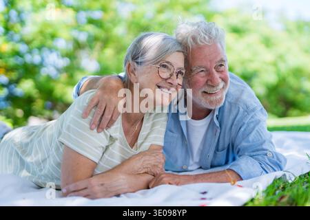 Wunderschönes, süßes Paar Senioren, die sich umarmen und einen zarten Moment draußen im grünen Park genießen und vor Glück lächeln. Zwei Rentner Stockfoto
