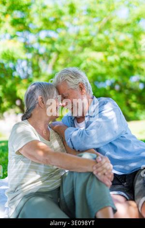 Wunderschönes, süßes Paar Senioren, die sich umarmen und einen zarten Moment draußen im grünen Park genießen und vor Glück lächeln. Zwei Rentner Stockfoto
