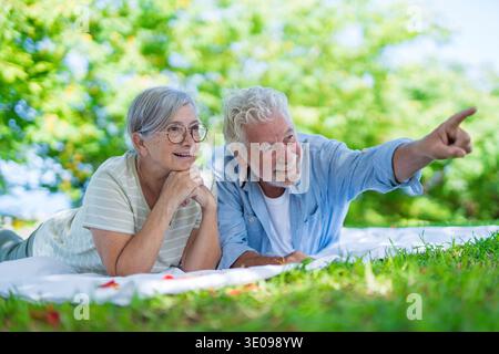 Wunderschönes, süßes Paar Senioren, die sich umarmen und einen zarten Moment draußen im grünen Park genießen und vor Glück lächeln. Zwei Rentner Stockfoto