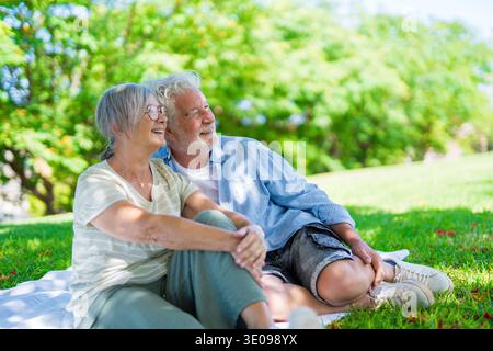 Wunderschönes, süßes Paar Senioren, die sich umarmen und einen zarten Moment draußen im grünen Park genießen und vor Glück lächeln. Zwei Rentner Stockfoto