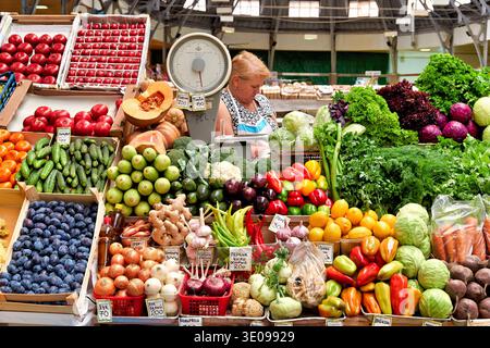 Eine Frau kauft frisches Obst und Gemüse auf dem Kuznechnyy Rynok Markt in Sankt Petersburg, Russland. Viele farbenfrohe Gegenstände sind zu sehen. Stockfoto