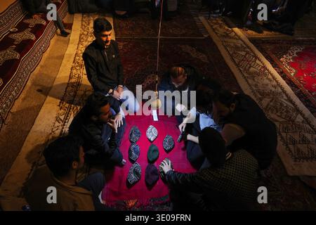Erbil, Irak. März 2026. Irakische kurdische Männer spielen das traditionelle Folklore-Spiel Klaw Klawne (Caps Game) während einer Ramadan-Nacht im Mali Hassan Hayran, einem historischen Schlammhaus im Shanidar Park in Erbil, Irak. Nach Iftar versammeln sich die Einheimischen, um das beliebte Ratespiel zu spielen, ein geschätzter Ramadan-Brauch, der das kulturelle Erbe der Region Kurdistan bewahren soll Foto von Sabur Rashid/ABACAPRESS.COM Credit: Abaca Press/Alamy Live News Stockfoto