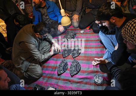 Erbil, Irak. März 2026. Irakische kurdische Männer spielen das traditionelle Folklore-Spiel Klaw Klawne (Caps Game) während einer Ramadan-Nacht im Mali Hassan Hayran, einem historischen Schlammhaus im Shanidar Park in Erbil, Irak. Nach Iftar versammeln sich die Einheimischen, um das beliebte Ratespiel zu spielen, ein geschätzter Ramadan-Brauch, der das kulturelle Erbe der Region Kurdistan bewahren soll Foto von Sabur Rashid/ABACAPRESS.COM Credit: Abaca Press/Alamy Live News Stockfoto
