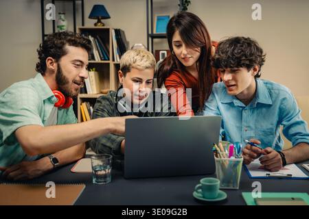 Eine vielfältige Gruppe von jungen Fachkräften arbeitet während einer Mentoring- und Wissensaustausch-Sitzung in einer modernen Büroumgebung mit einem Laptop zusammen. Stockfoto
