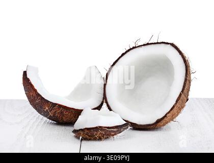 Gebrochene Kokosnuss auf Holztisch auf weißem Hintergrund. Stockfoto