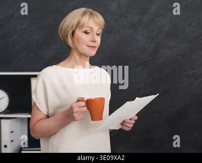 Porträt einer Reifen Geschäftsfrau, die im Büro Dokumente liest Stockfoto