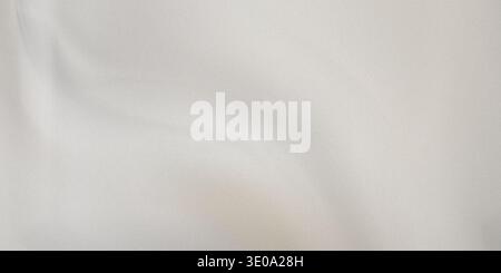 Dieses Bild zeigt eine detaillierte Nahaufnahme eines glatten weißen Stoffes mit sanften Falten und Falten, die seine Weichheit und Textur hervorheben. Die Fabric-App Stockfoto