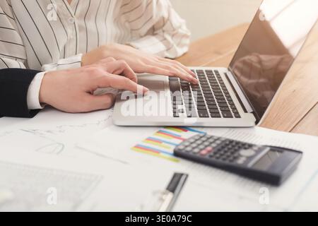 Geschäftskollegen tippen auf Laptop und überprüfen Diagramme Stockfoto