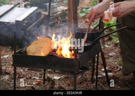 Kochspeck in einer Pfanne auf einem Holzfeuer im Freien. Stockfoto