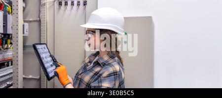 Ingenieurin arbeitet mit Tablet in hellem Technikraum. Frau Ingenieurin der Energiesteuerung. Stockfoto