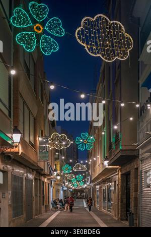 Festliche Weihnachtslichter in Form von Klee und Wolken erleuchten am Abend eine enge Fußgängerzone in Villarreal, Castellon, Spanien. Stockfoto