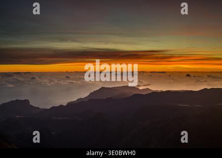 Am Pico do Arieiro offenbart ein atemberaubender Sonnenuntergang einen lebendigen Himmel voller Orange- und Violetöne. Die Berge darunter schaffen eine dramatische Landschaft, Stockfoto