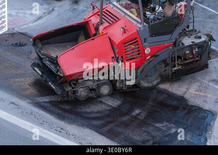 Asphaltfertiger Maschine, die frischen Asphalt auf der Stadtstraße legt Stockfoto