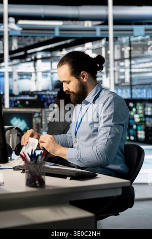 Server-Hub-Spezialist, der sich die Unterlagen zu Geschäftsdaten ansieht, um Probleme mit der Geräteleistung zu ermitteln. Rechenzentrumsmitarbeiter betrachten Analysediagramme für Dokumentdateien, um Hardwareausfälle zu reduzieren Stockfoto