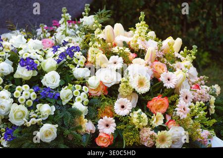 Üppige Blumenarrangements mit Rosen, Gerberas und Tulpen am Grab. Sympathie-Blumen auf dem Friedhof Melaten in Köln Stockfoto