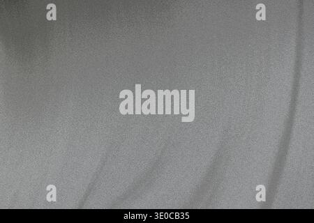 Das Bild zeigt eine detaillierte Nahaufnahme eines hellgrauen Stoffes mit einer glatten Textur und subtilen Falten. Die Beleuchtung ist gleichmäßig und hebt die Stoffe hervor Stockfoto
