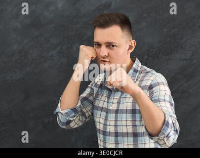 Junger Mann, der auf schwarzem Atelierhintergrund schlägt Stockfoto
