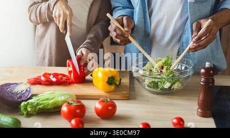 Schwarzes Paar bereitet Gemüsesalat zusammen vor Stockfoto