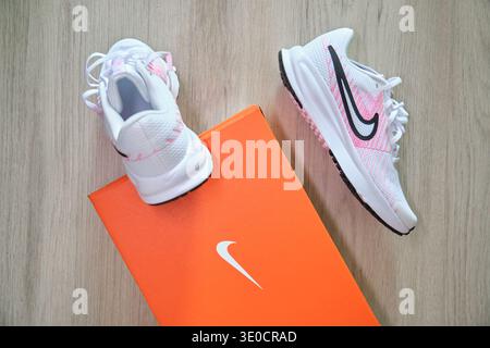 Neue weiße und pinkfarbene nike Running Sneakers mit orangefarbenem Schuhkarton auf einer Holzoberfläche Stockfoto