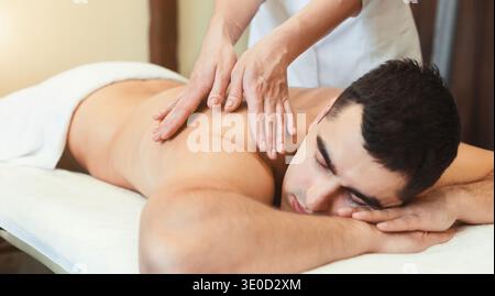 Porträt eines gutaussehenden Mannes, der eine Rückenmassage erhält Stockfoto