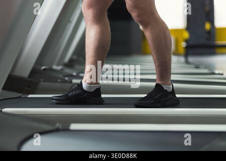 Nahaufnahme der Beine des Fitnessmannes, die im Fitnessstudio auf dem Laufband laufen Stockfoto