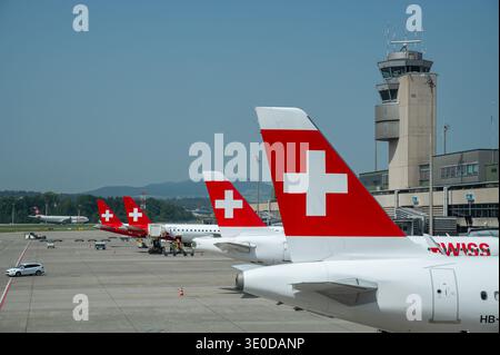 13.08.2025, Schweiz, Zuerich, - Passagierflugzeuge der Swiss Airlines und Helvetic Airways parken an ihren Ständen vor dem ter Stockfoto