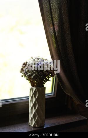 Wunderschöner Strauß von wilden getrockneten Blumen in einer Keramikvase auf der Fensterbank. Leerzeichen für Text Stockfoto