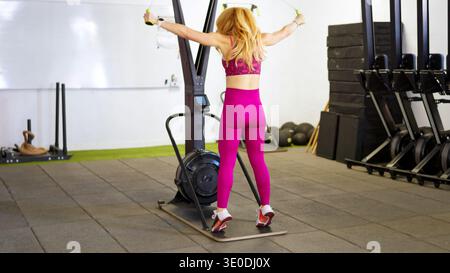 Die Frau trainiert auf der Skirg-Maschine im Fitnessstudio Stockfoto