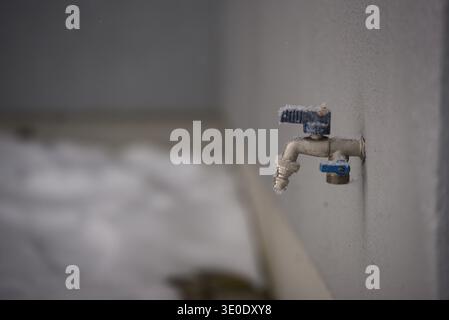 Nahaufnahme eines Metallwasserhahns im Freien mit Frostbildung am Ventil bei kaltem Winterwetter. Konzeptbild für Gefriertemperaturen, Sanitär i Stockfoto