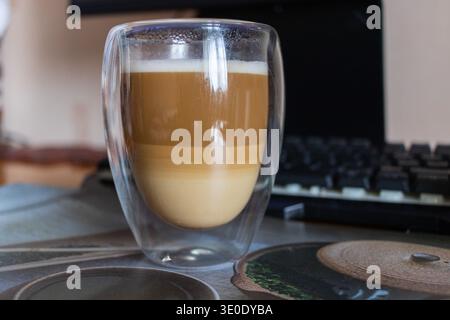 Eine köstliche dreischichtige Kaffeespezialität in einer Thermoglasschale. Das Getränk zeigt eine klare Trennung zwischen aufgeschäumter Milch, Espresso und aufgeschäumter Milch i Stockfoto