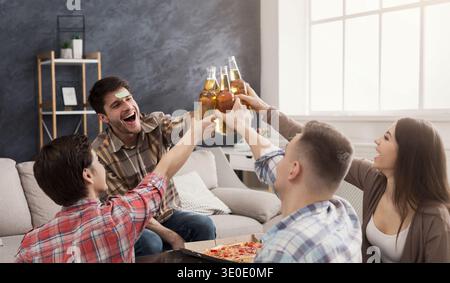 Vier glückliche Freunde, die Bierflaschen anstoßen Stockfoto