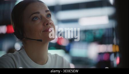 Woman Broker verwaltet den Workflow auf Multimonitor Trading Station nahtlos. Frauen, die ein Headset tragen, berichten aktiv Echtzeit-Marktdaten und besprechen Investitionsstrategien. Multitasking in Exchange. Stockfoto