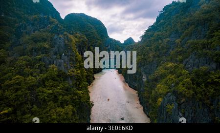 Aus der Vogelperspektive auf türkisfarbenes Wasser treffen auf zerklüftete Klippen, die von smaragdgrünem Grün bedeckt sind, ein verstecktes Paradies, das von oben enthüllt wird: El Nido, Mimaropa, Philippinen. Stockfoto