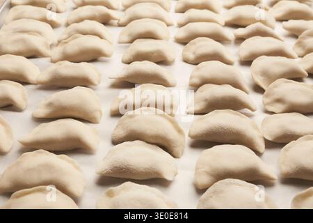 Auf einem Tablett angeordnete Knödel, bevor sie in der Küche kochen Stockfoto