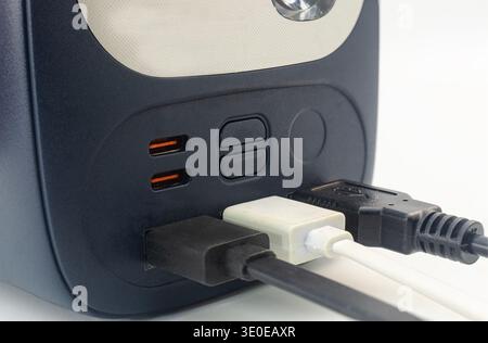 Nahaufnahme mehrerer USB- und USB-C-Kabel, die an eine tragbare Powerbank oder einen Solargenerator angeschlossen sind, zeigt moderne Konnektivität und mobile Energie Stockfoto